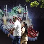 An Iranian couple walk past a huge anti-Israeli banner carrying pictures of missiles on Iran&#39;s map, in Tehran, Iran, 19 April 2024. Iranian state media reported that three aerial objects were destroyed by air defense systems over the central city of Isfahan early morning on 19 April. 