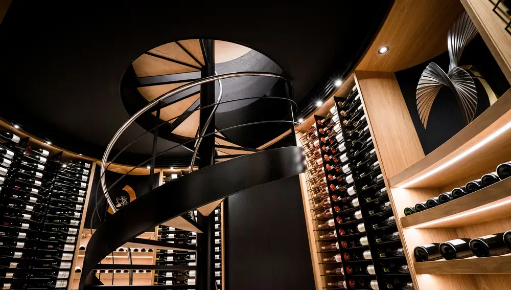 Imagen de la bodega, con más de 7.500 botellas de vinos de todo el mundo, y su peculiar escalera de caracol