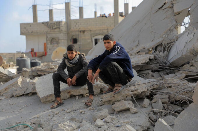 Dos paletinos se sientan entre los escombros de un bombardeo israelí en el sur de Gaza
