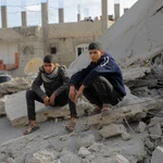 Dos paletinos se sientan entre los escombros de un bombardeo israelí en el sur de Gaza