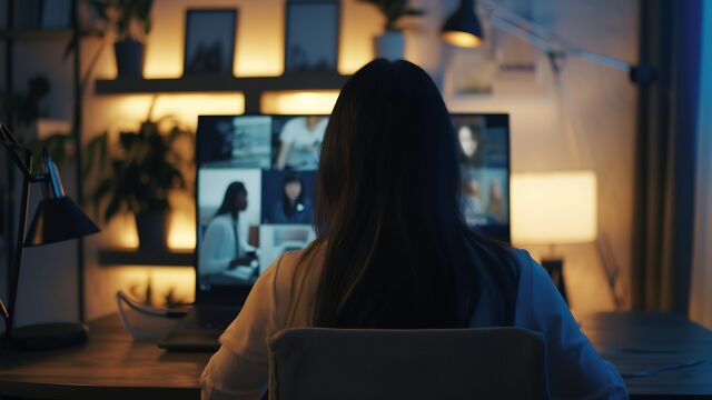 Mujer hablando en videollamada con diversos colegas en una sesión informativa en línea