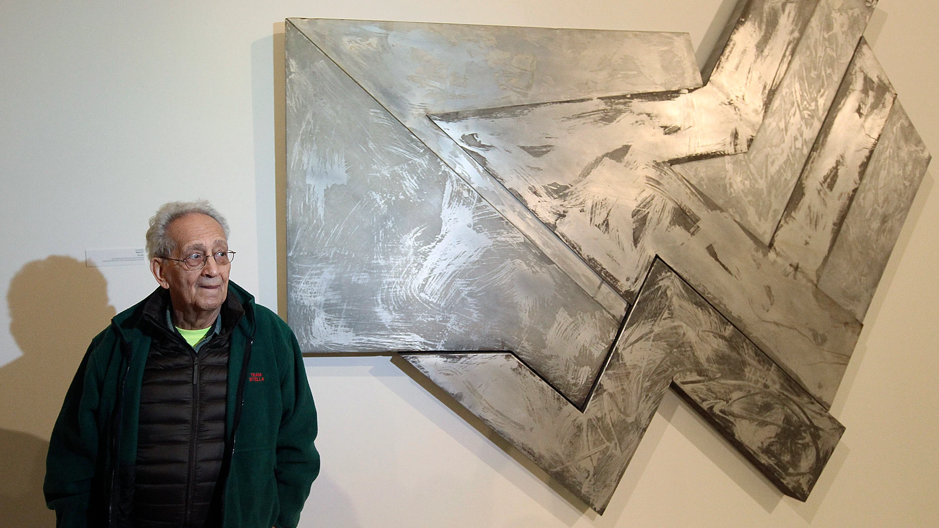 FILE - U.S. artist Frank Stella stands in front of one of his works at an exhibition devoted to him in Warsaw, Poland, Feb. 18, 2016. Stella, a painter, sculptor and printmaker whose constantly evolving works are hailed as landmarks of the minimalist and post-painterly abstraction art movements, died Saturday, May 4, 2024, at his home in Manhattan. He was 87. (AP Photo/Czarek Sokolowski, File)