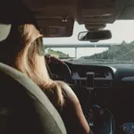 Mujer conduciendo un coche en una autopista.
