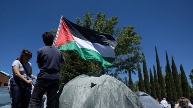 Dos estudiantes con una bandera de Palestina durante una acampada para mostrar su apoyo al pueblo palestino y exigir el fin del conflicto en Gaza en la Complutense de Madrid