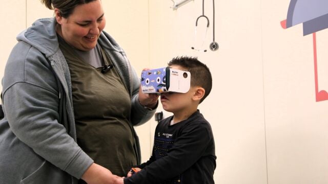 Aran coge de la mano a su madre mientras se prepara para su intervención visualizando el vídeo de realidad virtual de Nixi