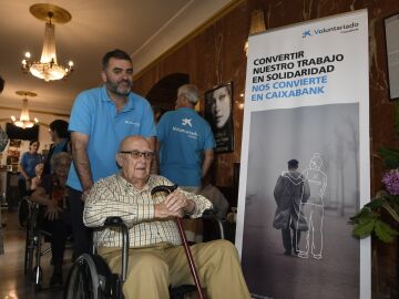 Un voluntario asiste a un usuario de la residencia de mayores Gerón de Sevilla en el cine Cervantes de Sevilla