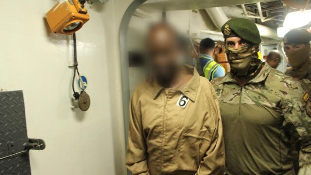 Un militar español traslada a uno de los piratas detenidos