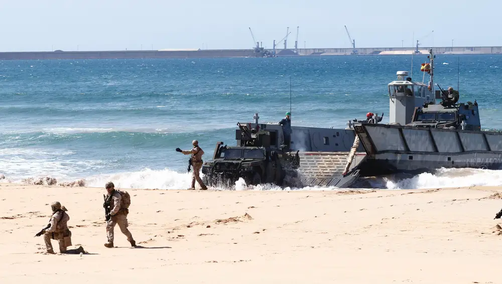 Vehículos y militares salen de una de las lanchas de desembarco de la Armada en la playa de Gijón