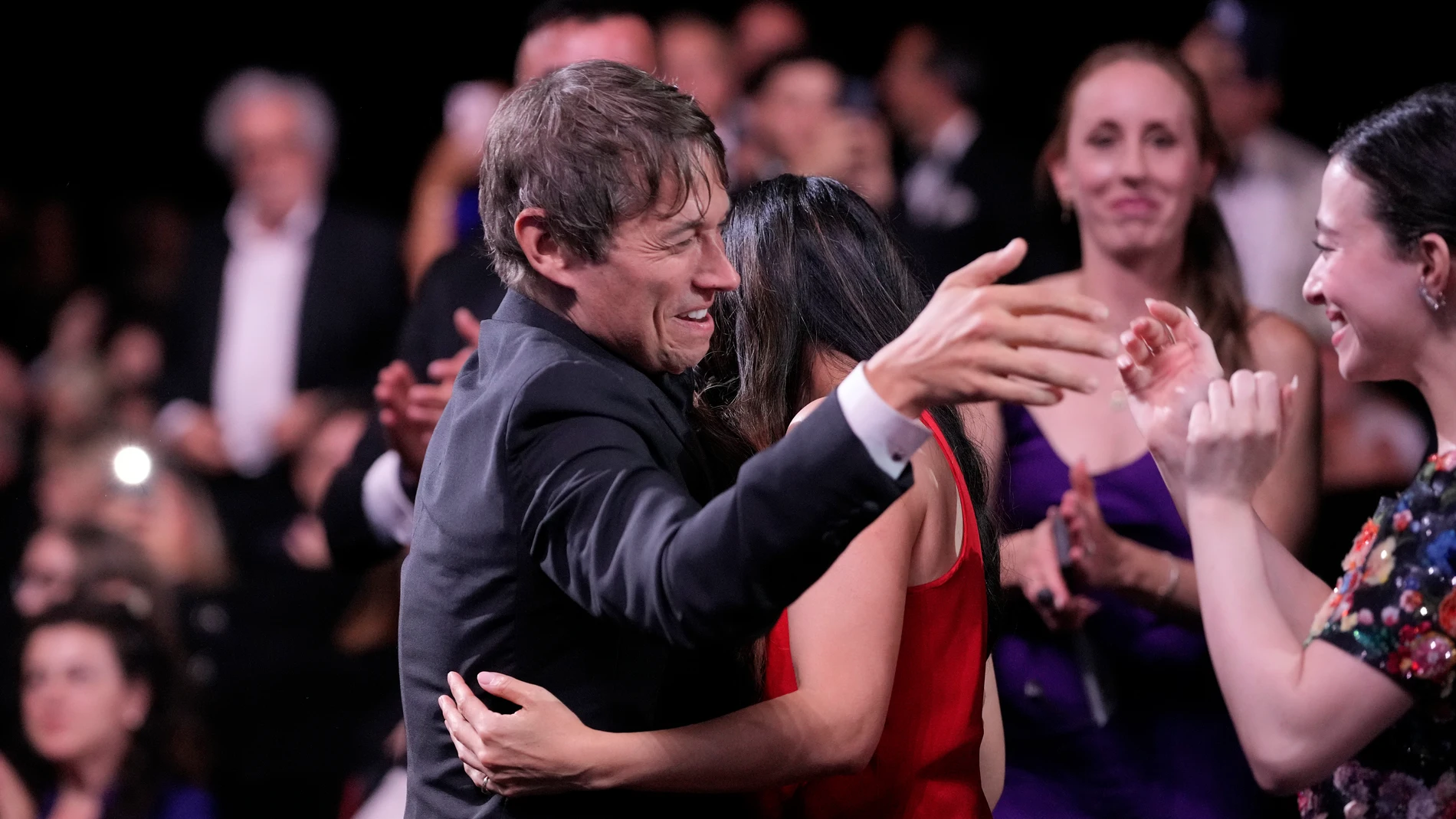 Sean Baker, centre, is embraced prior to accepting the Palme d'Or for the film 'Anora,' during the awards ceremony of the 77th international film festival, Cannes, southern France, Saturday, May 25, 2024 (Photo by Andreea Alexandru/Invision/AP)