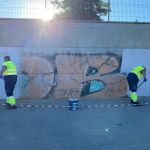 Operarios municipales limpian una pared