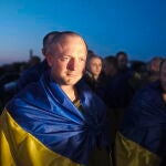 Un grupo de prisioneros de guerra ucranianos envueltos en la bandera azul y amarilla tras su puesta en libertad
