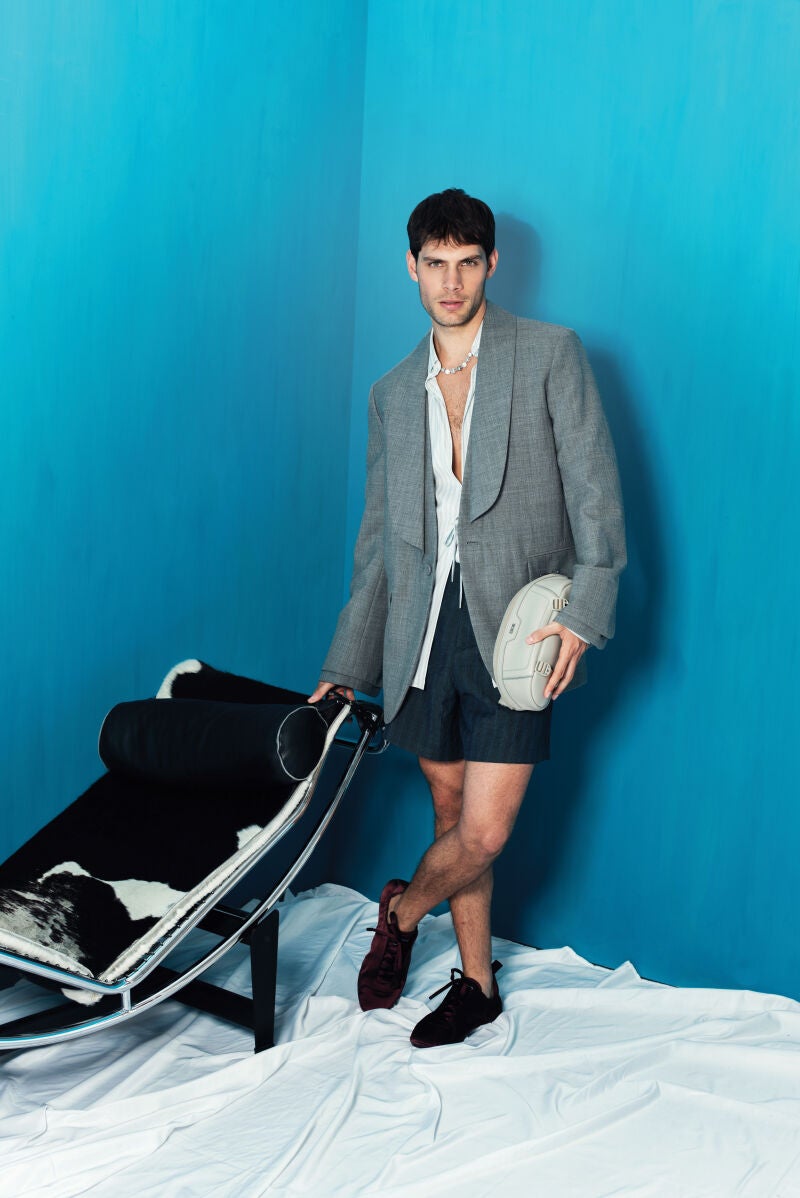 Pol Hermoso con chaqueta, camisa, pantalón corto, mocasines, collar y riñonera de Dior Men