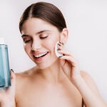 Una mujer se limpia la cara con agua micelar