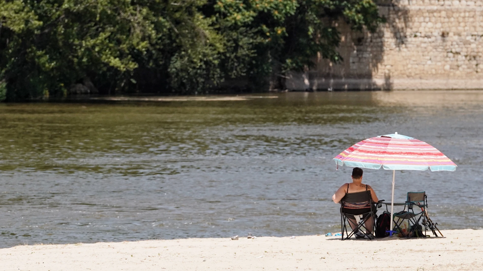 Una mujer toma el sol en la playa de las Moreras de Valladolid
