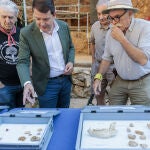 El presidente Alfonso Fernández Mañueco observa las piezas junto a los codirectores del yacimiento