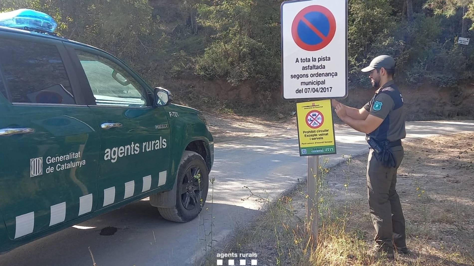 Un agente de Agents Rurals coloca una señal para restringir el acceso a una zona en elevado riesgo de incendio AGENTS RURALS 29/07/2024