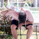 Un joven vertiéndose agua para refrescarse de la ola de calor