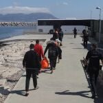 Varios migrantes son conducidos a un autobús tras desembarcar en Cádiz