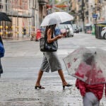 Varias personas caminan bajo la lluvia por una calle del centro de Valencia