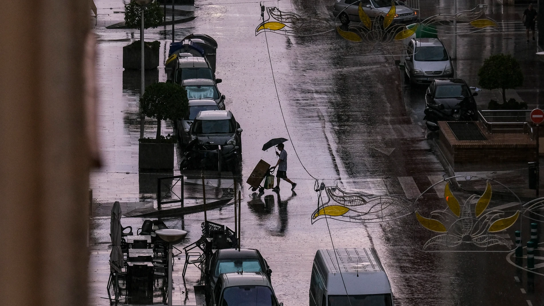-FOTODELDÍA- ELCHE (ALICANTE), 14/08/2024.- Un hombre cruza una calle en del centro de Elche mientras cae un fuerte aguacero. La Aemet ha establecido el aviso naranja para este miércoles por tormentas con probable granizo y rachas muy fuertes de viento en toda la provincia de Alicante y en el sur de Valencia. EFE/Pablo Miranzo