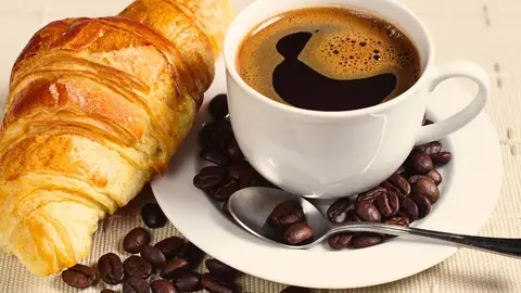 Un cruasán con una taza de café