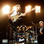 Sting, left, bassist and lead singer of the rock band, The Police, leaps in the air as he performs with Andy Summers, guitarist, and drummer Stewart Copeland, founding member of the band, at the Staples Center in Los Angeles