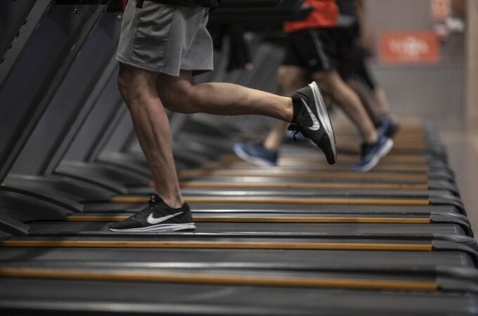 Gente corriendo en la cinta de un gimnasio.