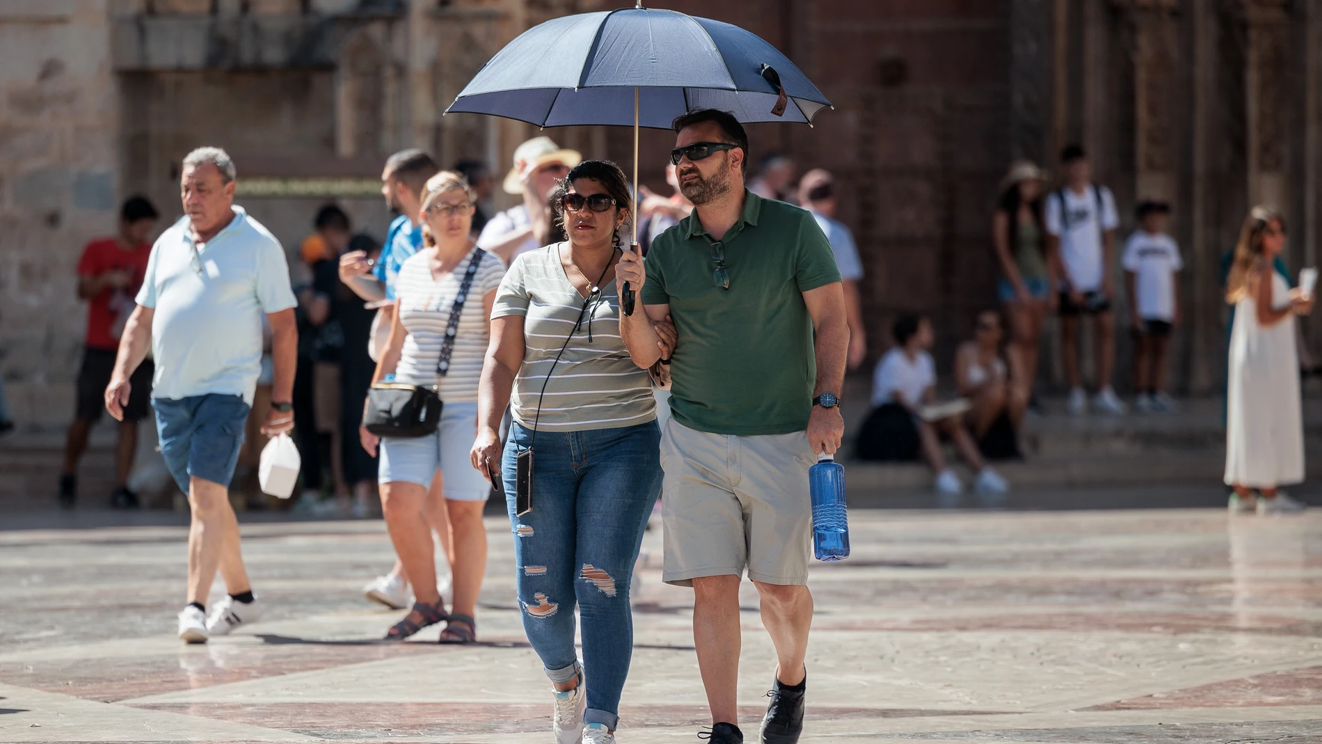 VALENCIA, 17/08/2024.- Unas personas se protegen del calor con una sombrilla este sábado en Valencia. El cielo de la Comunitat Valenciana presentará este sábado un aspecto poco nuboso o despejado, con temperaturas mínimas con pocos cambios y máximas en ascenso, viento flojo variable, tendiendo al mediodía a viento moderado de sur y sureste en el litoral y flojo de componentes sur y este en el interior. En la imagen, dos turistas se protegen del sol con un paraguas en el centro histórico de Va...