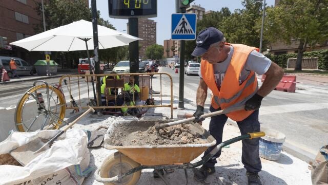 Un trabajador de la construcción junto a un termómetro que marca cuarenta grados en la avenida de la Fama de Murcia.