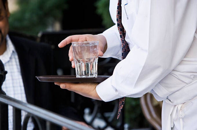 Un camarero con un vaso de agua