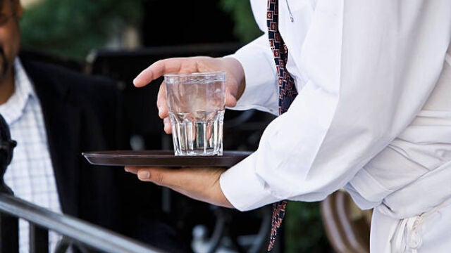 Un camarero con un vaso de agua