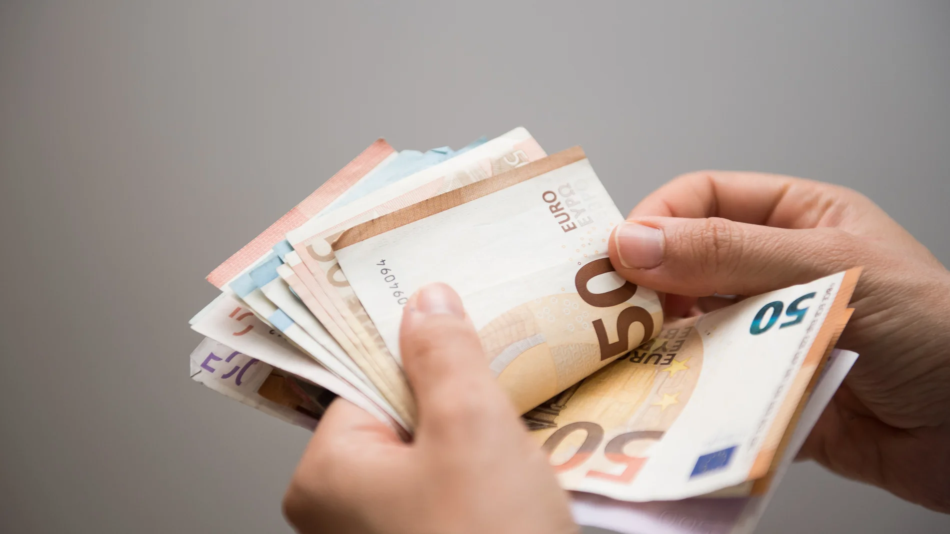 Persona contando un fajo de billetes de euros