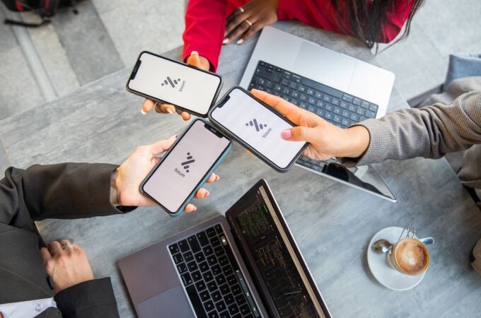 Three businesswomen during a meeting pay the bill with Bizum, a fast money exchange system.
