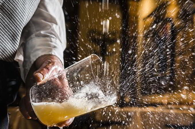 Un profesional escancia un culín de sidra.