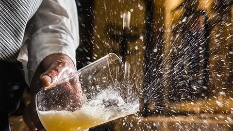 Un profesional escancia un culín de sidra.