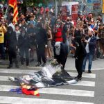 Jóvenes independentistas antisistema quemando retratos y banderas