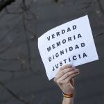 Una persona reivindica con un cartel "verdad, memoria, dignidad y justicia" 