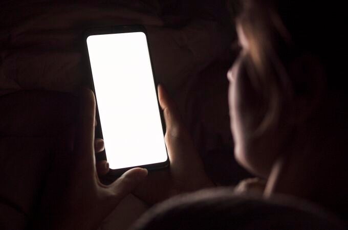 Una mujer recibe la luz del teléfono móvil por la noche