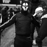 Un policía registra a un radical enmascarado en Walthamstow, en el este de Londres durante las protestas que tuvieron lugar en agosto