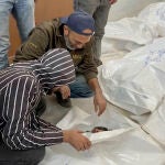 Palestinos revisan una bolsa para cadáveres de un familiar fallecido en un ataque aéreo de Israel