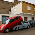 Una persona pasa junto a unos coches amontonados debido a las lluvias torrenciales que afectan a la Comunitat Valenciana, y especialmente a la provincia de Valencia