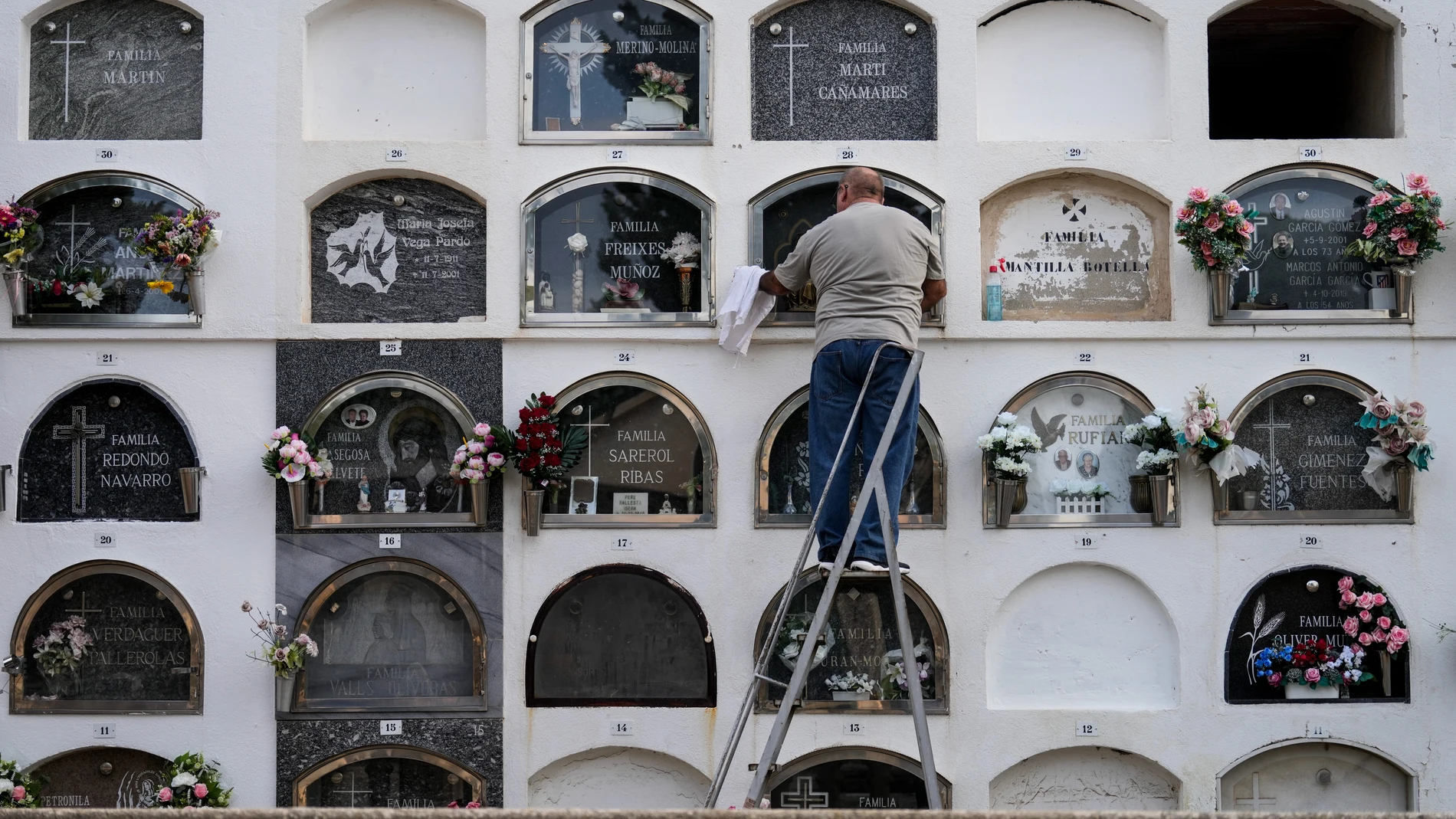 BARCELONA, 01/11/2024.- Un hombre limpia un nicho del céntrico cementerio de la población de El Masnou, Barcelona, este viernes, Día de Todos los Santos. EFE/Enric Fontcuberta