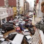 A woman looks out from her balcony as vehicles are trapped in the street after flooding in Valencia, Wednesday, Oct. 30, 2024. 