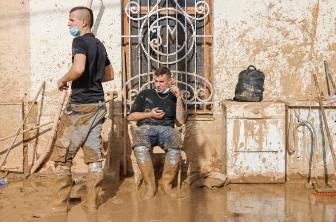 Voluntarios barren el lodo de una calle de Masanasa, Valencia, hoy jueves