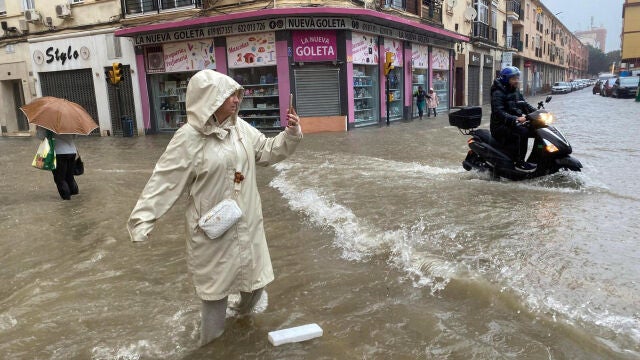 Una mujer realiza una fotografía en una calle inundada de la capital malagueña, ayer durante las intensas lluvias provocadas por la DANA