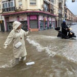 Una mujer realiza una fotografía en una calle inundada de la capital malagueña, ayer durante las intensas lluvias provocadas por la DANA