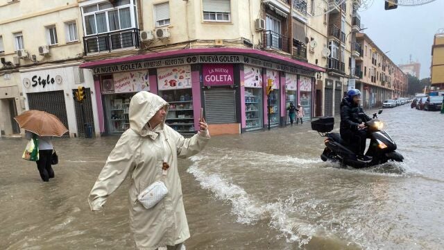 Una mujer hace fotos con el agua hasta las rodillas en Málaga donde las fuertes trombas de agua y granizo que se registran este miércoles han causado inundaciones y la acumulación de grandes balsas en algunas de las principales avenidas de todos los distritos de la ciudad.