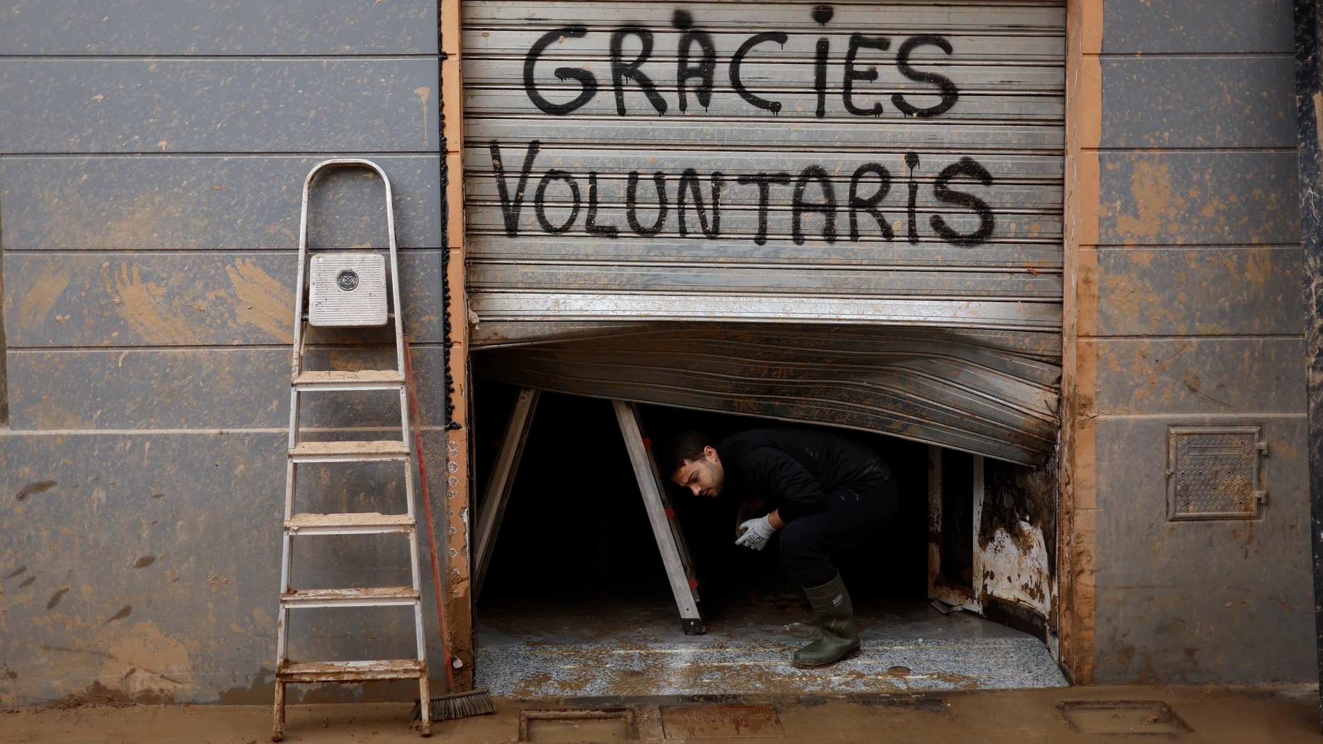 -FOTODELDÍA- PAIPORTA(VALENCIA), 18/11/2024.- Persiana dañada por las riadas con el texto 'Gracies voluntaris' en Paiporta, este lunes. Una decena de centros educativos de municipios de la zona cero de la dana que asoló Valencia hace veinte días reinician sus clases en otro paso del lento camino hacia una cierta normalidad para las familias afectadas, mientras empresas y trabajadores reciben asesoramiento público para afrontar las consecuencias laborales de una tragedia que deja ya 219 víctim...