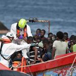 Trabajadores ayudan a los migrantes que llegan en patera al puerto de La Restinga, trasladados por Salvamento Marítimo, a 26 de julio de 2024, en El Hierro, Canarias