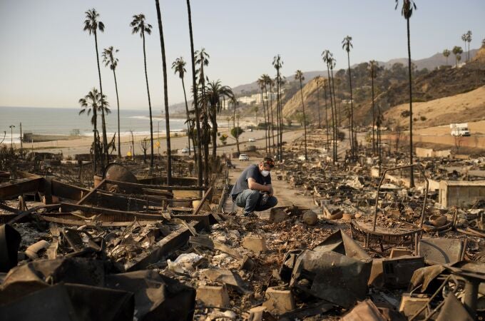 Kevin Marshall sifts through his mother's fire-ravaged property in the the Palisades Fire in the Pacific Palisades neighborhood of Los Angeles, Saturday, Jan. 11, 2025. (AP Photo/John Locher)